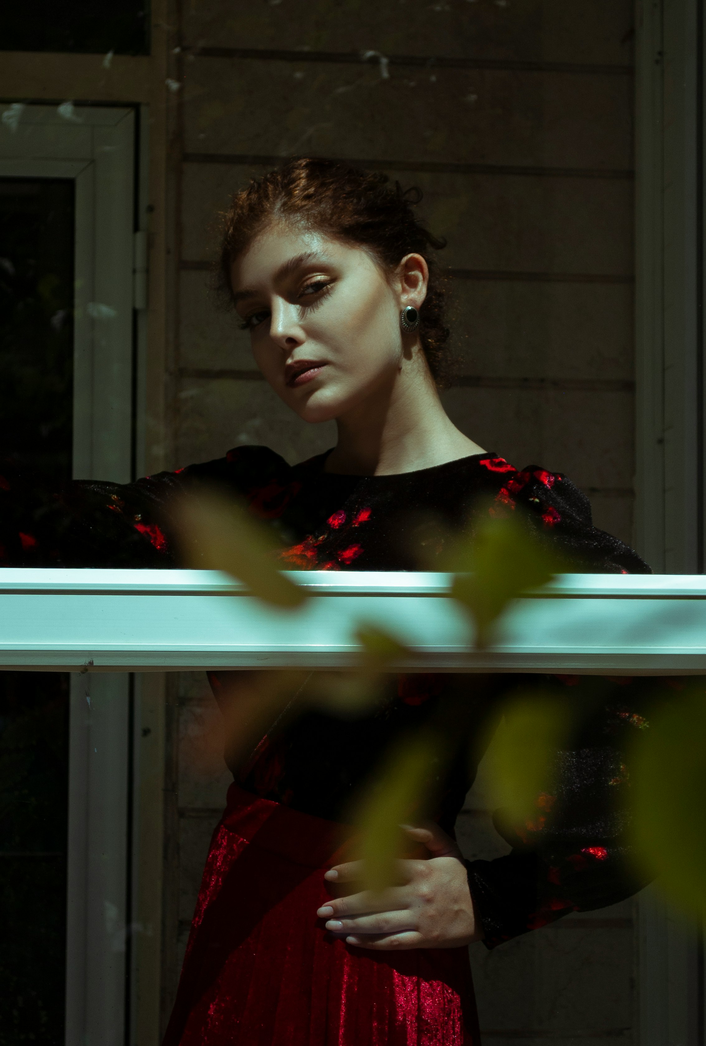 woman in red dress standing near window